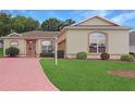 Charming single-story home featuring a brick driveway, well-manicured lawn, and lovely landscaping at 5008 Sawgrass Lake Cir, Leesburg, FL 34748