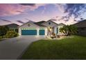 Charming single-story home at dusk with a three-car garage, pretty landscaping, and inviting curb appeal at 5746 Botner Dr, The Villages, FL 32163