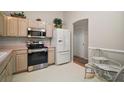 Bright kitchen with white appliances, wood cabinets, and adjacent breakfast nook at 1007 Diego Ct, The Villages, FL 32159