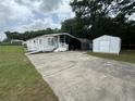 Large concrete driveway leading up to a charming single Gathering home with two storage buildings at 10905 Se 127Th Ln, Belleview, FL 34420