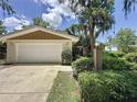 Home exterior features attached two-car garage, stone accents, and lush landscaping at 11401 Cypress Dr, Clermont, FL 34711