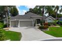 Charming single-story home with a three-car garage, beautiful landscaping, and mature palm trees in a suburban neighborhood at 1335 Eureka Mill Run, The Villages, FL 32162