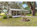 Charming single-story home featuring a stone-accented front, inviting porch seating, and a cozy fire pit area at 1436 Spring Lake Rd, Fruitland Park, FL 34731