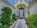 Inviting front entrance with a decorative archway, lush greenery, and a well-lit walkway at 17037 Se 76Th Creekside Cir, The Villages, FL 32162