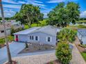 An aerial view of a light blue house featuring mature trees, a landscaped yard, and a long driveway at 25007 Bellevue, Leesburg, FL 34748