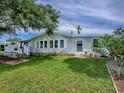 Lovely home exterior featuring a green lawn, white trim, and partially shaded deck at 25007 Bellevue, Leesburg, FL 34748