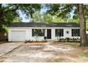 A charming single-story home features a black front door, dark shutters and well maintained landscaping at 25824 Shawnee St, Sorrento, FL 32776