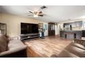 Spacious living room with wood flooring, a ceiling fan, and seamlessly connected to the kitchen area at 25824 Shawnee St, Sorrento, FL 32776