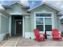 Inviting front porch area with two red chairs and attractive front door with windows and wreath at 2648 Maymont Ct, The Villages, FL 32163