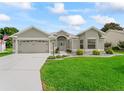 Beautiful home featuring a well-maintained lawn, gray concrete driveway, attached garage, and landscaped front yard at 3057 Saint Thomas Ln, The Villages, FL 32162