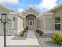 Inviting front entrance featuring a walkway lined with rocks and plants leading to a gray home at 3057 Saint Thomas Ln, The Villages, FL 32162