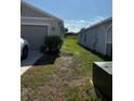 View of side yard with grass leading to backyard with a house behind it under blue sky at 3260 Casa Del Rey Ave, Kissimmee, FL 34746