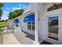 Inviting home entrance featuring a glass door, blue awnings, and wrought iron gate at 6036 Topsail Rd, Lady Lake, FL 32159