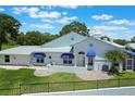 Charming single-story home featuring a white exterior, blue awnings, and a well-manicured lawn at 6036 Topsail Rd, Lady Lake, FL 32159