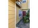 A yellow townhouse with white trim, a red front door, and lush tropical landscaping at 624 Australian Way, Davenport, FL 33897