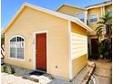Inviting yellow house with a prominent red door, complemented by bright white trim and a 'hello' doormat at 624 Australian Way, Davenport, FL 33897