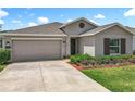 Charming single-story home featuring a well-manicured lawn and a two-car garage with neutral stucco exterior at 6946 Perch Hammock Loop, Groveland, FL 34736
