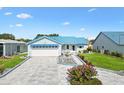 Inviting single-story home with blue roof and awnings, lovely landscaping, and an extended driveway at 714 Prado Dr, The Villages, FL 32159