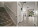 Entryway showcases staircase and tile flooring leading to an open living space with sliding glass doors to the backyard at 9153 Carmela Ave, Davenport, FL 33897