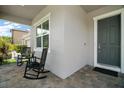 Inviting front porch featuring rocking chairs, a small table, and a gray brick floor at 9153 Carmela Ave, Davenport, FL 33897