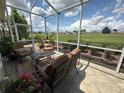 Screened lanai featuring comfortable outdoor furniture and a peaceful view of the landscaped backyard at 12183 Se 178Th St, Summerfield, FL 34491