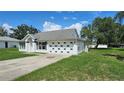 Well-maintained single-story home featuring a classic white facade and large garage, on a sunny day at 12512 Draw Dr Dr, Grand Island, FL 32735
