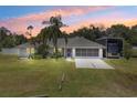Charming single-story home with well-maintained lawn, mature landscaping, and spacious driveway at dusk at 135 N James Pl, Groveland, FL 34736