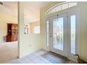 Bright entryway featuring tile floors, decorative glass door, and view of dining and living room at 13700 Se 90Th Ct, Summerfield, FL 34491