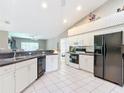Spacious kitchen featuring white cabinets, black appliances, and tile flooring at 13700 Se 90Th Ct, Summerfield, FL 34491