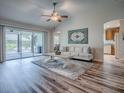 Open living room with hardwood flooring, ceiling fan, sliders to the lanai, and neutral decor at 1419 Arbor Trl, The Villages, FL 32162