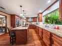 Beautiful kitchen featuring wood floors, custom cabinets, granite countertops, an island with barstool seating, and modern appliances at 15733 Tower View Dr, Clermont, FL 34711