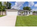 Inviting single-story home with a lush green lawn and a spacious two-car garage at 15828 Se 98Th Ter, Summerfield, FL 34491