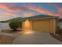 Home at sunset with a well manicured lawn, beautiful shrub, and a two car garage at 2101 Southern Star Way, The Villages, FL 32162