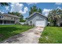 Well-kept home with an attached garage, long driveway, and a front yard filled with flowers and a mature palm tree at 2110 Churchill Downs Cir, Orlando, FL 32825