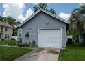 Attached garage of gray single-story home with a well-maintained lawn and colorful flower bed at 2110 Churchill Downs Cir, Orlando, FL 32825