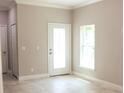 Neutral-toned living room with a decorative glass front door and tiled flooring at 2114 Waitman Ave Waitman, Leesburg, FL 34748