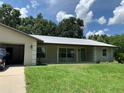Beautiful front exterior featuring a metal roof, inviting porch with rocking chairs, and lush green lawn at 2530 Shady Ln, Groveland, FL 34736