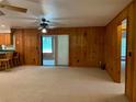 Spacious living room with wood paneling, carpeted floors, and a sliding glass door to a porch at 2530 Shady Ln, Groveland, FL 34736