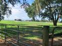 Scenic view of the expansive pasture and farm buildings from the entrance gate of this country estate at 2530 Shady Ln, Groveland, FL 34736