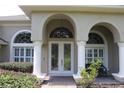 Elegant arched entryway with double doors and manicured landscaping accents at 31104 Fairvista Dr, Tavares, FL 32778