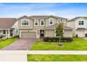 Beautiful two-story home with lush green lawn, a brick driveway, and manicured landscaping at 3304 Canna Lily Pl, Clermont, FL 34711