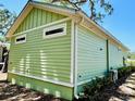Side view of home with green siding showing the roofline and some foliage at 3607 Umbrella Tree Ln, Oxford, FL 34484