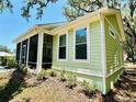 Side view of a charming home showcasing a screened porch, windows, and lush landscaping at 3607 Umbrella Tree Ln, Oxford, FL 34484