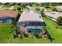 Aerial view of a home with a screened pool, surrounded by manicured lawn and lush landscaping at 5418 Sandy Hill Ln, Lady Lake, FL 32159