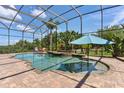 Stunning screened pool with a spa and brick surround, complemented by tropical landscaping and outdoor seating at 5418 Sandy Hill Ln, Lady Lake, FL 32159
