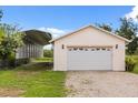 Detached garage with a large roll-up door, accented by exterior lighting and a gravel driveway at 5729 Bible Camp Rd, Groveland, FL 34736