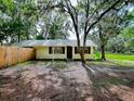 The front of the charming yellow single-story home, with lush mature trees draped in Spanish moss at 6731 Lake Griffin Rd, Lady Lake, FL 32159
