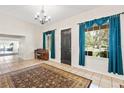 Grand entry boasts bright windows with blue curtains, a dark front door, tile floors and open access to other rooms at 81 N Carol Ave, Mascotte, FL 34753