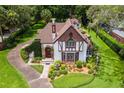 Charming Tudor-style home with manicured lawn, stone accents, and a classic fountain feature at 9233 Silver Lake Dr, Leesburg, FL 34788