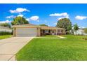 Charming single-story home with a well-manicured lawn and two-car garage, set against a backdrop of blue skies and fluffy clouds at 9790 Se 175Th St, Summerfield, FL 34491